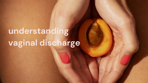Close-up of hands holding a halved apricot near the pelvic area with text "understanding vaginal discharge" on skin, symbolizing female reproductive health and vaginal discharge awareness.