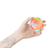 Hand holding Bodyotics Comfydisc Rainbow Edition reusable menstrual disc with pull-off string, colorful silicone design